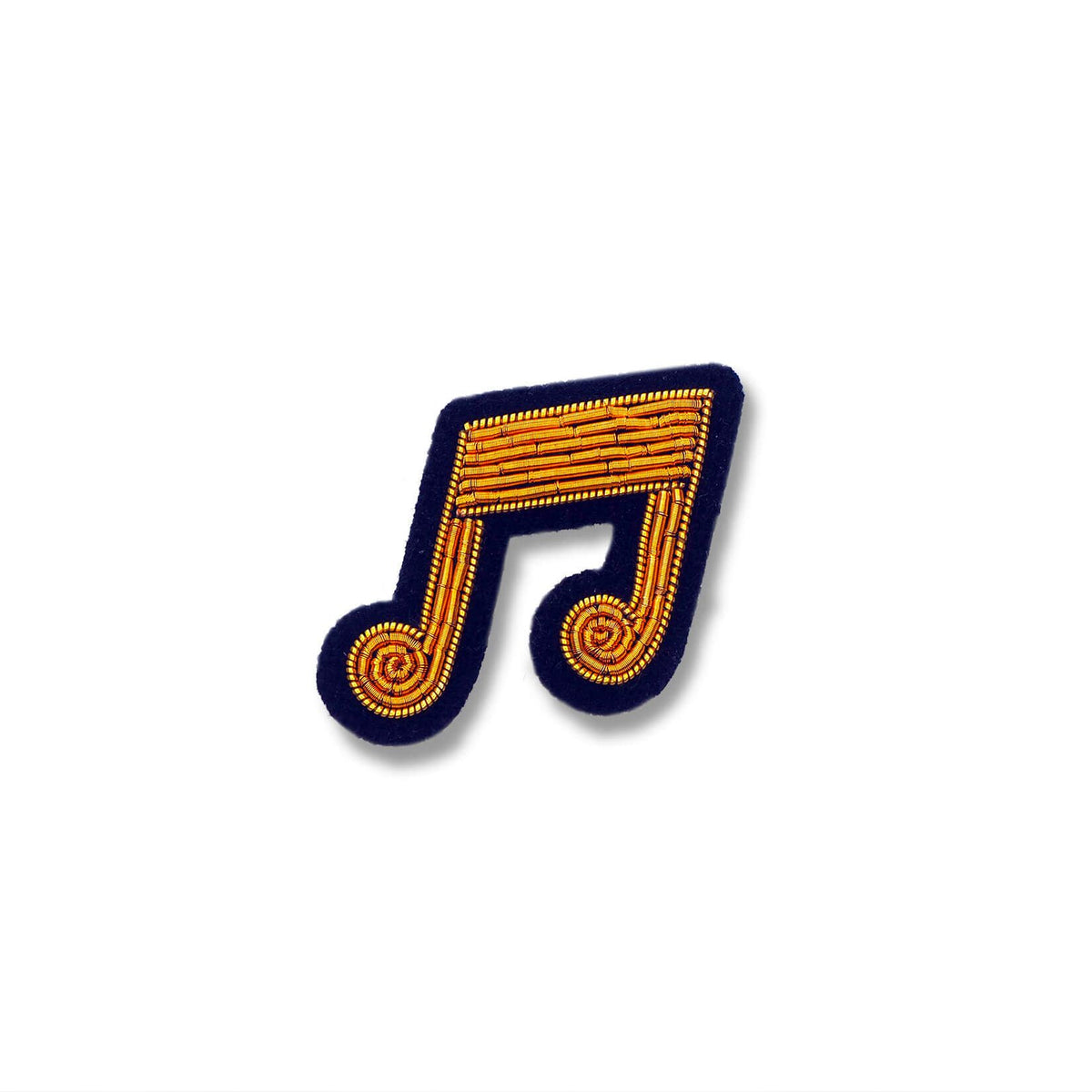 Macon & Lesquoy musical note lapel pin hand-embroidered in gold thread on a navy ground, photographed on a plain white background