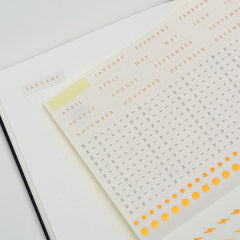 Supplied sticker sheet of months and markers laid across the dotted pages of the Bullet Journal Edition 2